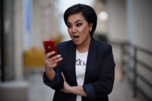 Mulher chocada segurando um celular. (Foto: Internet)