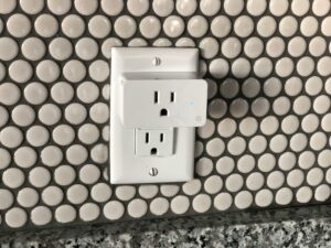 Close-up of a smart plug on a tiled wall showcasing contemporary interior design style.