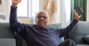 Idoso feliz com seu celular, que consegue encontrar facilmente imagens para o Whatsapp. (Foto: Pexels)