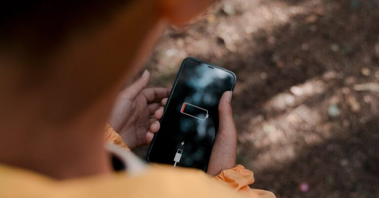 Rapaz segurando um celular sem bateria. (Foto: Pexels)