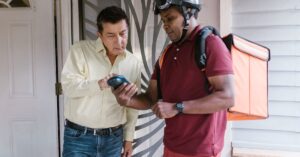 Homem conferindo o código do delivery junto ao entregador. (Foto: Pexels)