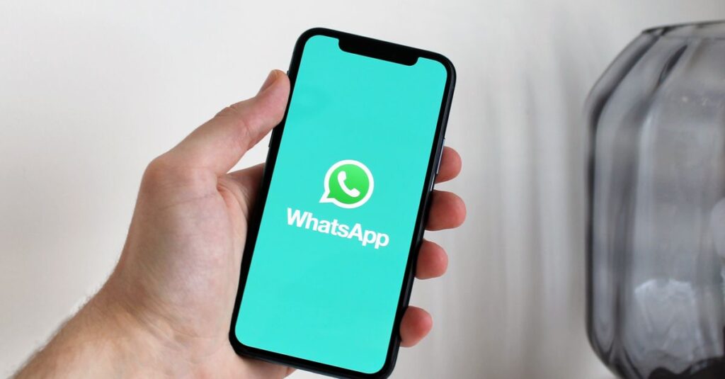 Close-up of a hand holding a smartphone displaying the WhatsApp app screen.