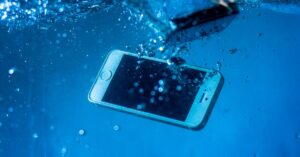 Celular mergulhado na água. (Foto: Pexels)