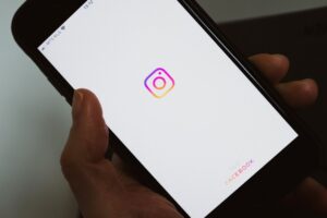 Mão segurando o smartphone com Instagram aberto. (Foto: Pexels)